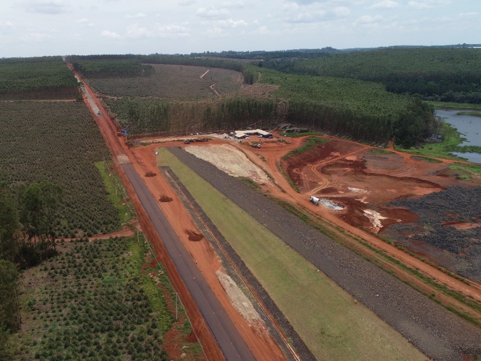 Aqui há uma foto aérea de uma obra de terraplenagem onde metade da estrada encontra-se sem pavimento e a outra metade já está pavimentada.