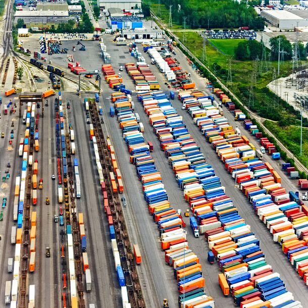 Aqui encontra-se uma foto aérea de um porto seco com uma grande quantia de contêineres que são utilizados para transporte de carga em larga escala, nacionalmente e internacionalmente.